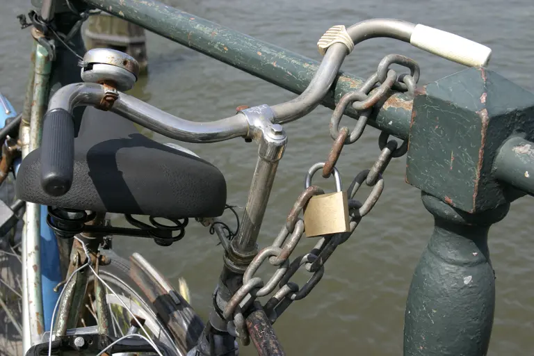Hardened chain lock securing a bicycle to a post.