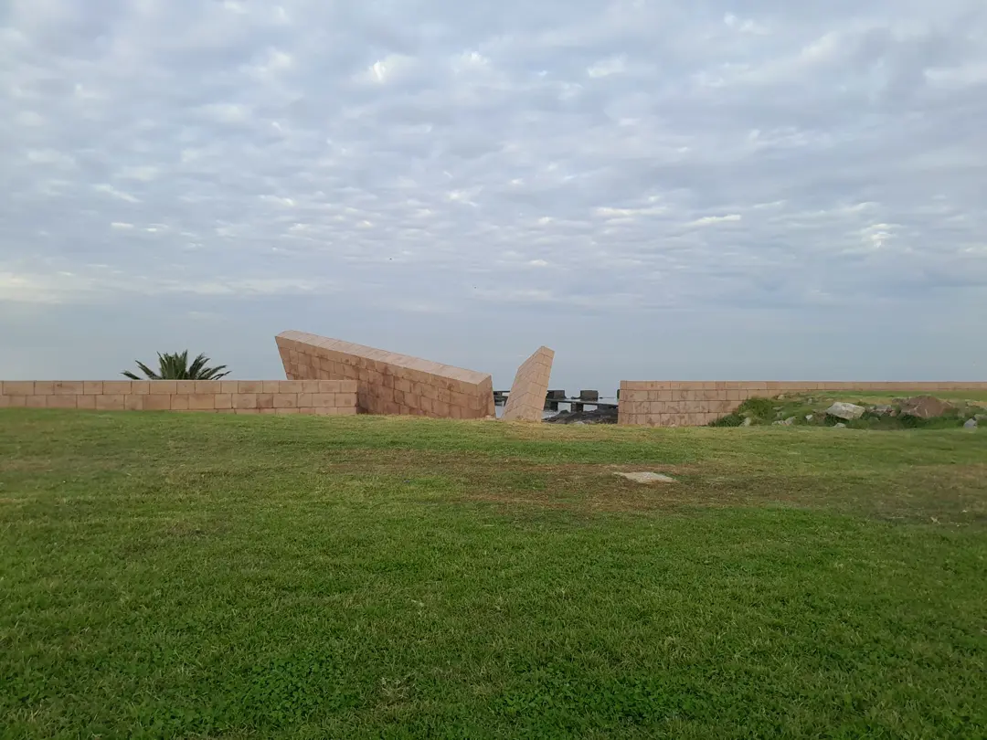The Holocaust Memorial wall seen from the front, on the lawn that slopes to the river.