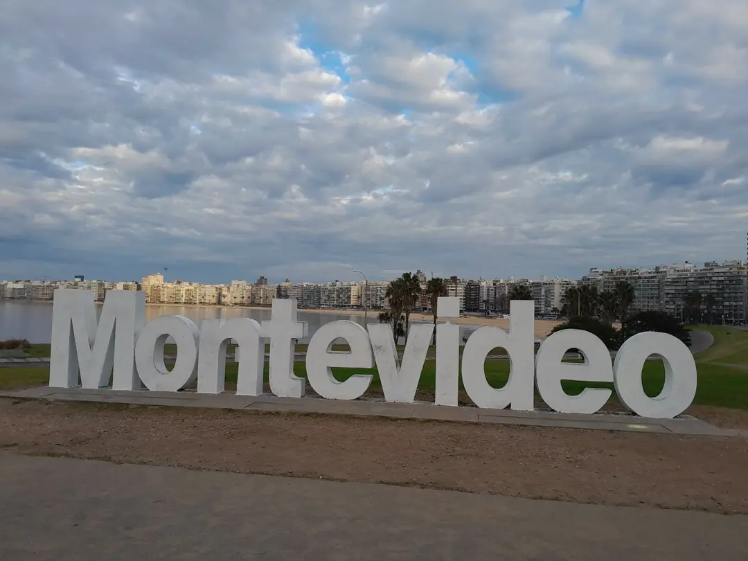 The MONTEVIDEO letters on the Pocitos rambla, with the beach and towers behind.